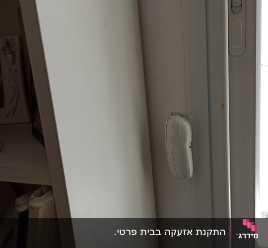 חיישן אבטחה מותקן על מסגרת חלון לבנה